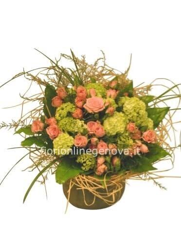 Cestino di vimini o ciotola di ceramica, composto da rose e verde pregiato.